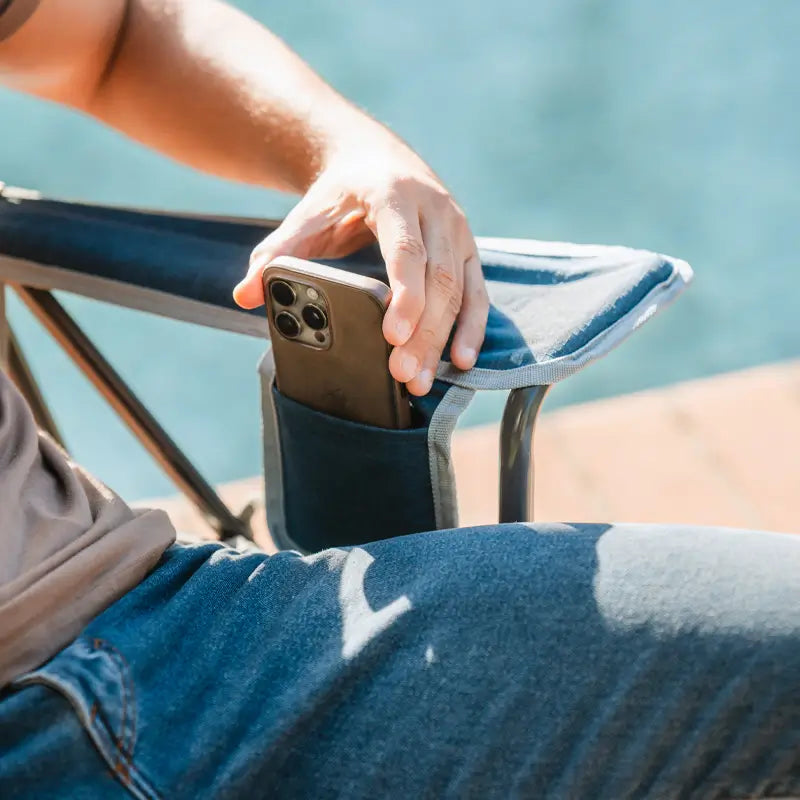 Man sliding phone into the armrest pocket of the heathered indigo Kickback Rocker.