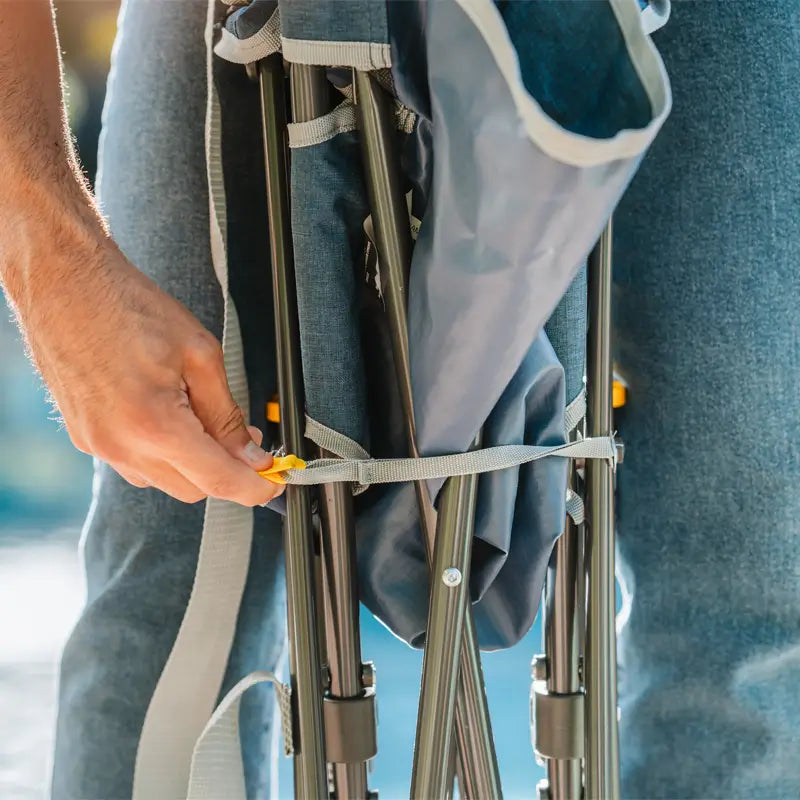 Close-up of hands securing folded heathered indigo Kickback Rocker using its strap.
