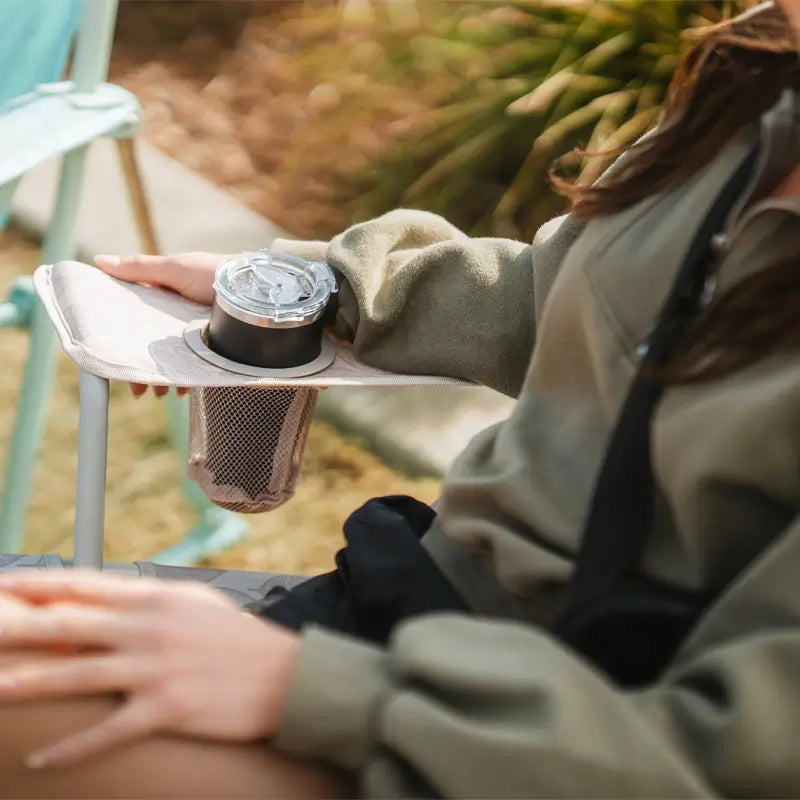 Close-up of a drink in the mesh cupholder of the Soft Neutral Leaf Kickback Rocker.