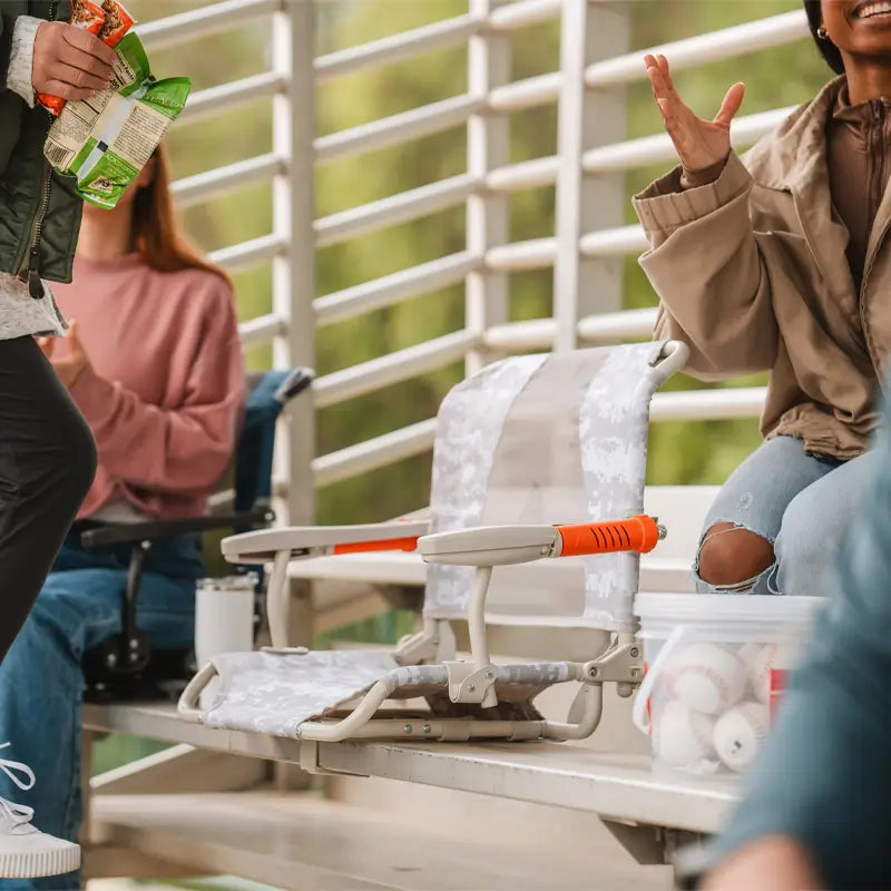 Two Snow Camo Stadium Rock-Cliners set up side-by-side during a game with people chatting nearby.