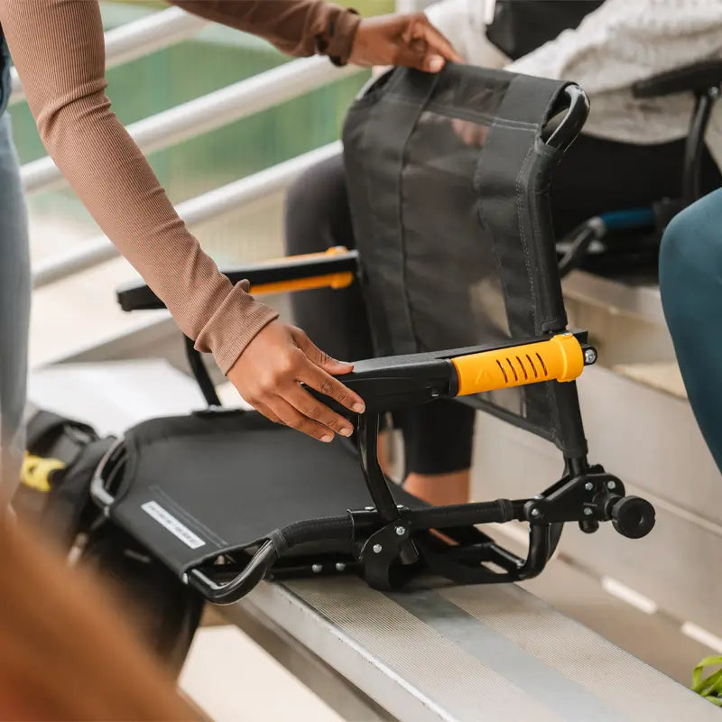 Woman setting up the dark charcoal Stadium Rock-Cliner on bleacher seating.