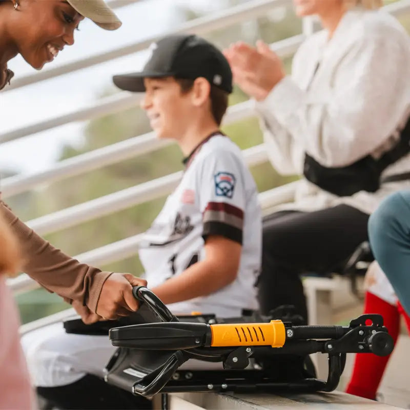 Smiling woman placing the folded dark charcoal Stadium Rock-Cliner on a bleacher bench.