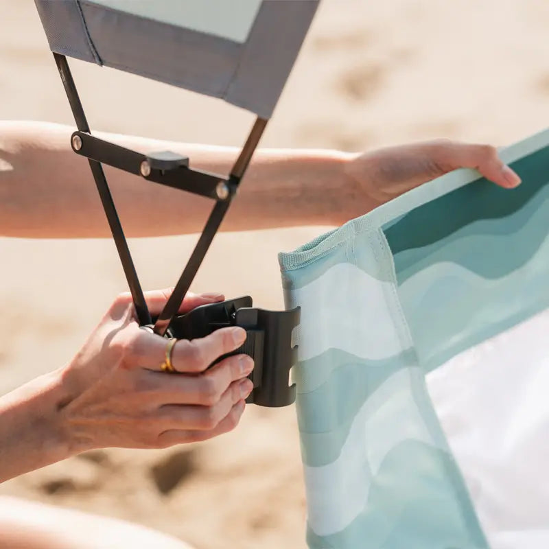Close-up of sunshade clamp attachment being secured to a pastel green-striped beach chair.