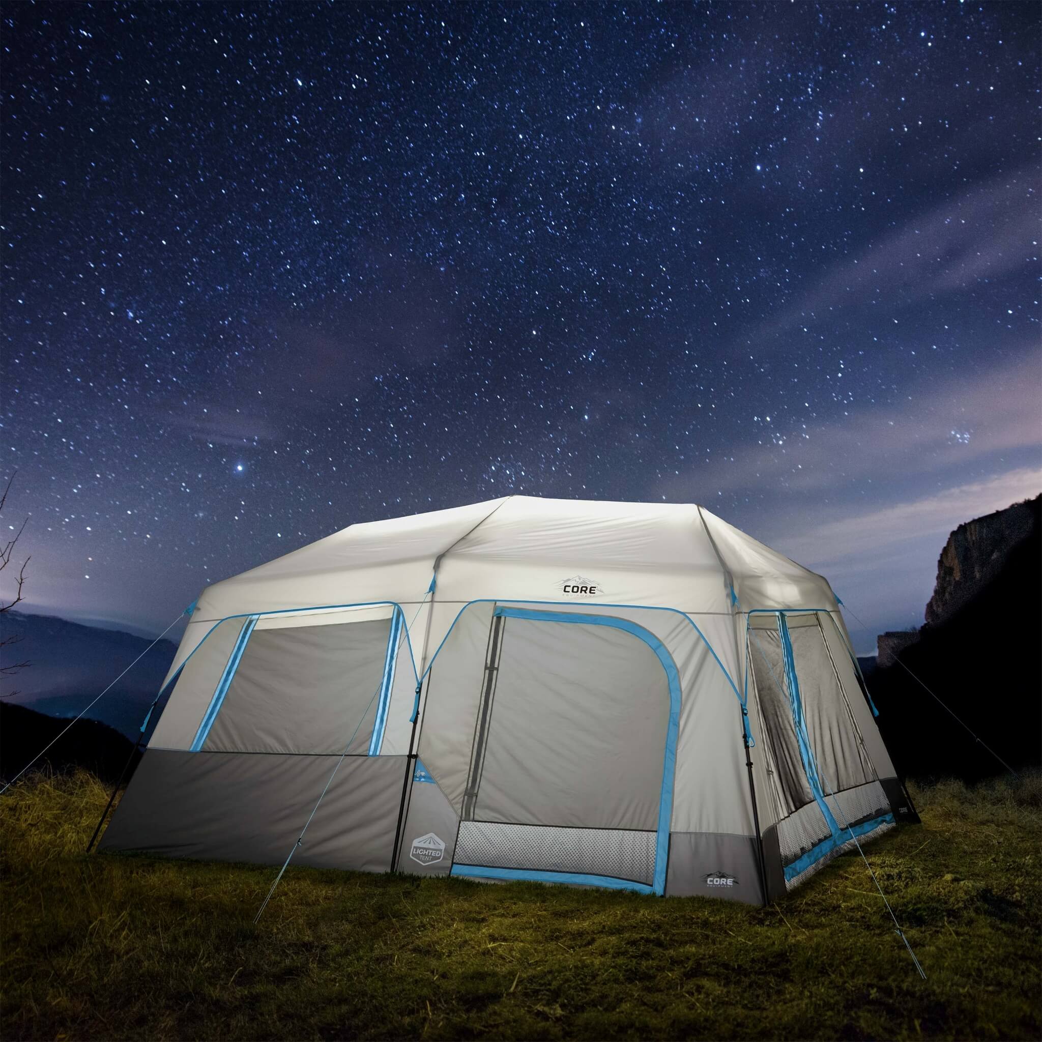 CORE 10 person lighted instant cabin tent in gray and blue, glowing at night, showing spacious design, weather protection, and LED lighting.