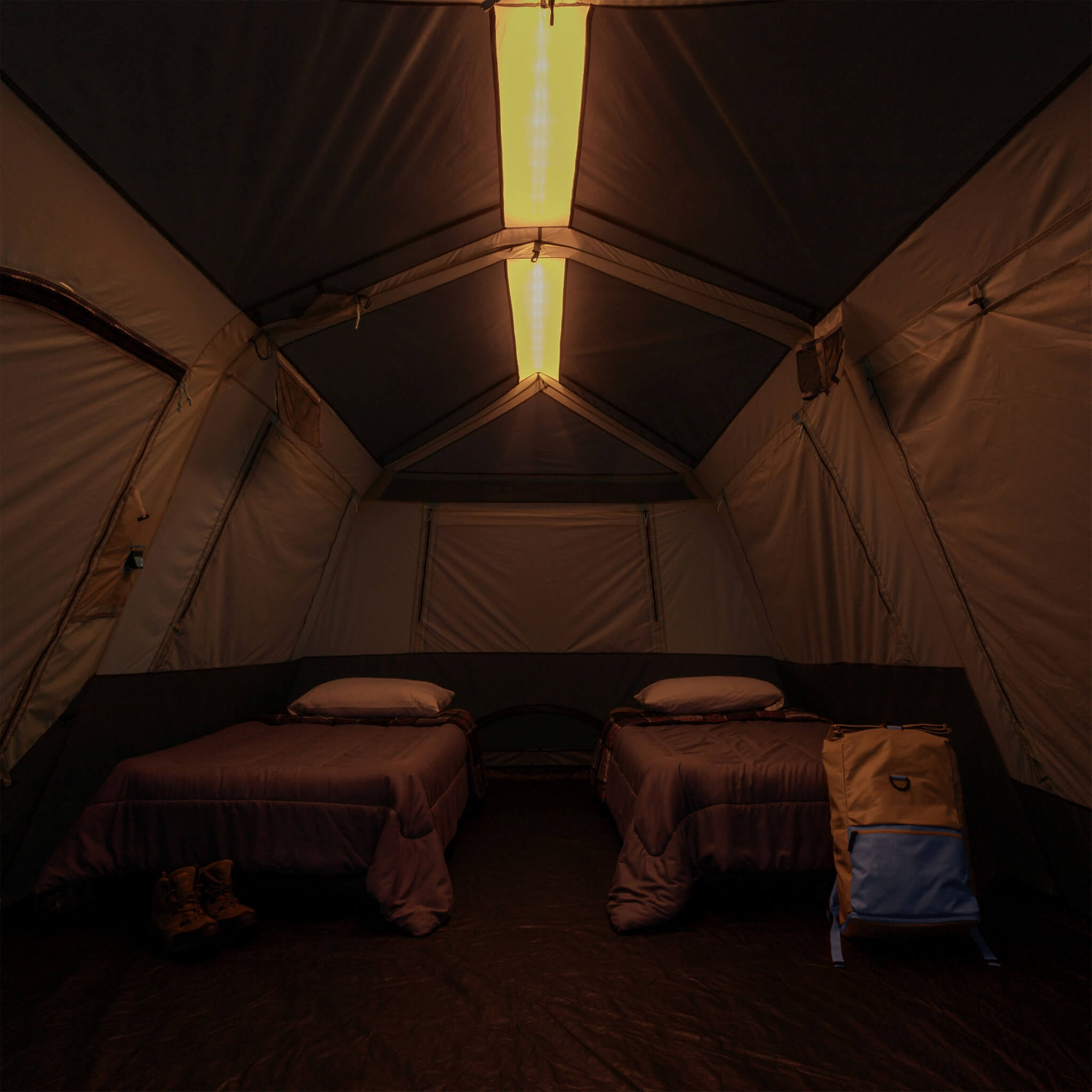 Inside CORE 10 person lighted instant cabin tent with air mattresses, showing overhead light bar on amber for nighttime visibility and comfort.