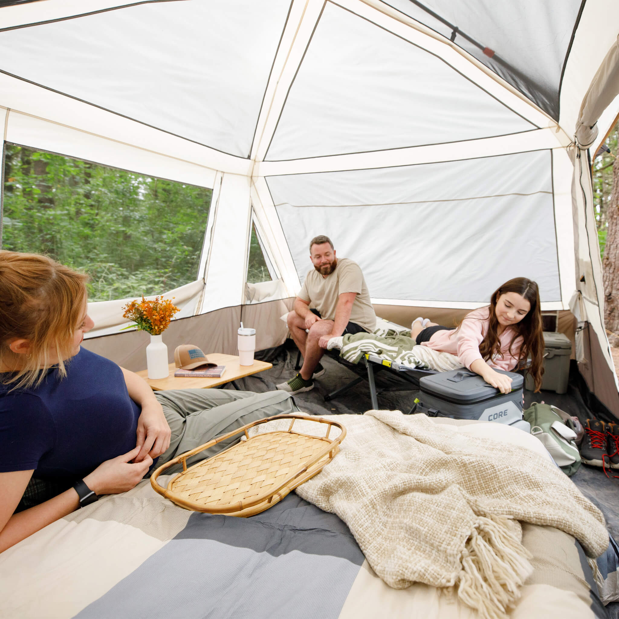 Family sitting inside CORE 10 person instant pyramid tent with tall ceiling, mesh windows, and spacious living area.