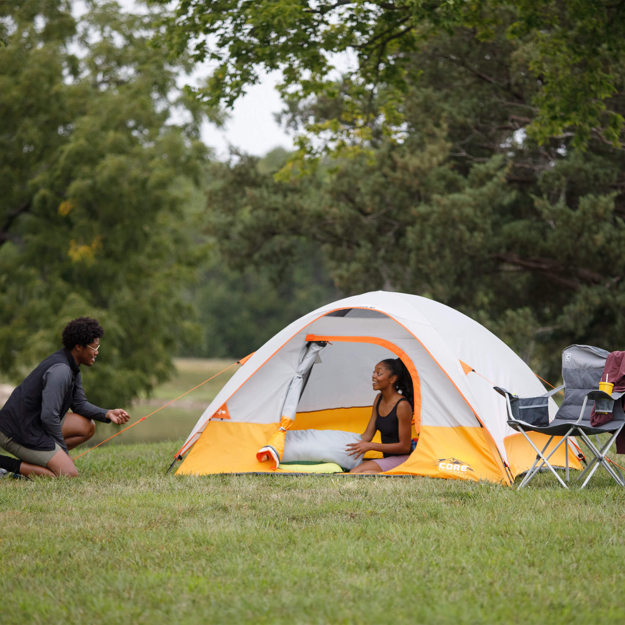 Campers relaxing beside CORE 4 person dome tent, ideal for weekend trips, parks, and outdoor adventures.