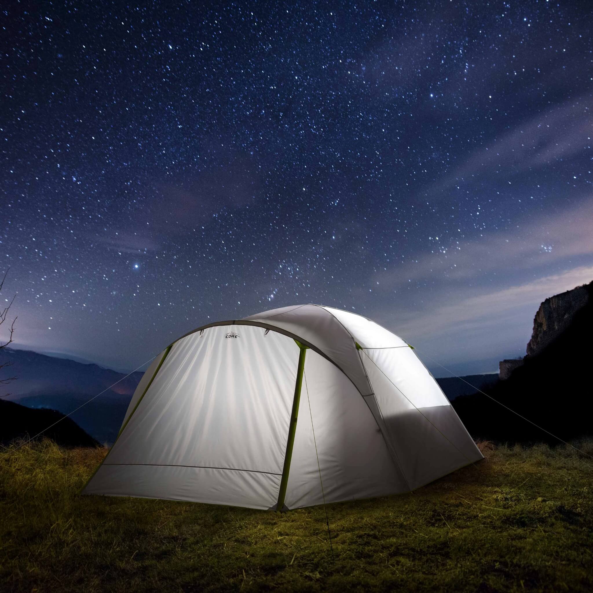 CORE 6 person lighted dome tent with full rainfly under a starry sky, offering outdoor shelter and weather protection.