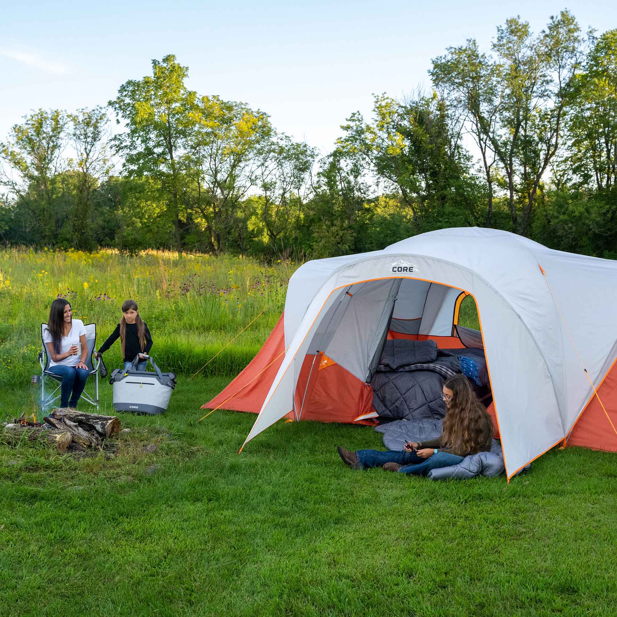 People camping outdoors with a CORE 9 person dome tent in a grassy area.