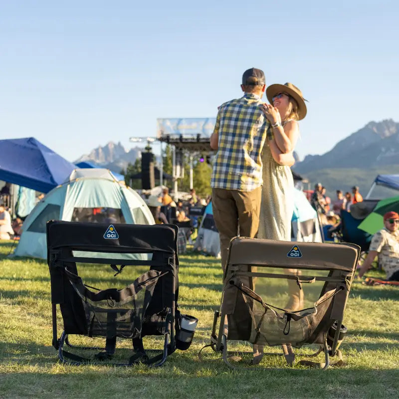 Two Everywhere Chair 2s set up on the grass with a couple dancing in the background at a festival.