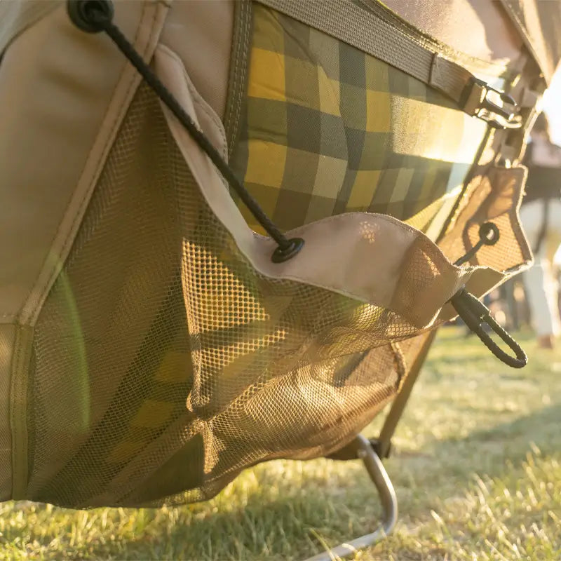 Close-up of mesh storage pocket on the aged fatigue Everywhere Chair 2 holding a plaid blanket.