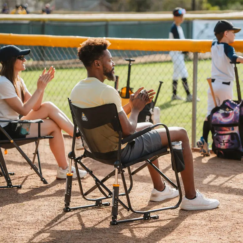 Spectators sit on Black Freestyle Rocker Elite chairs while watching a youth baseball game.