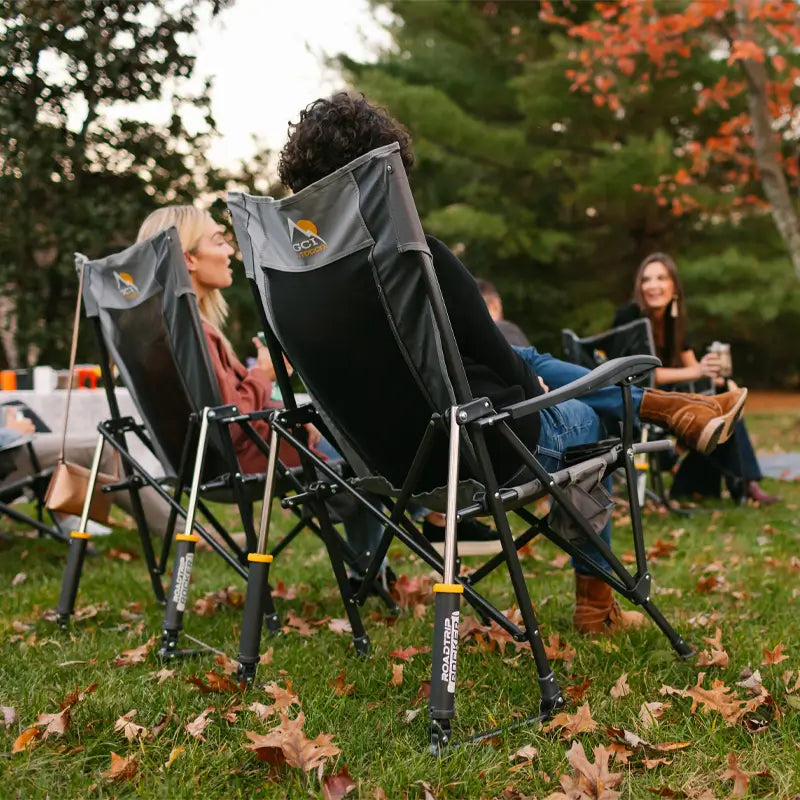Group chats outdoors in fall, seated in mercury gray Roadtrip Rocker chairs.