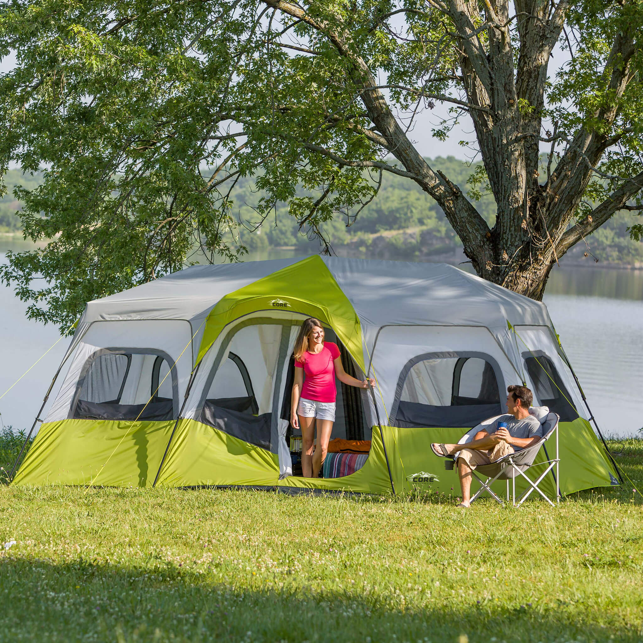 Campers relaxing beside the CORE 12 person instant cabin tent in gray and green, designed for fast setup and reliable weather protection.